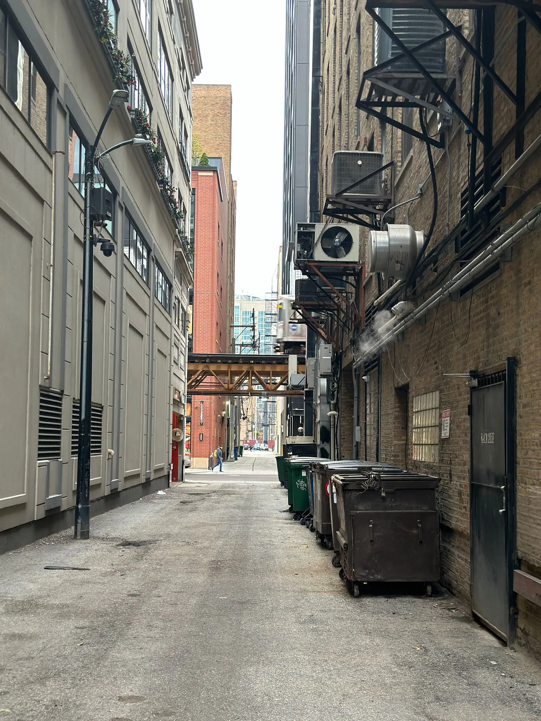 A narrow Chicago alley lined with brick walls, utility boxes and garbage bins