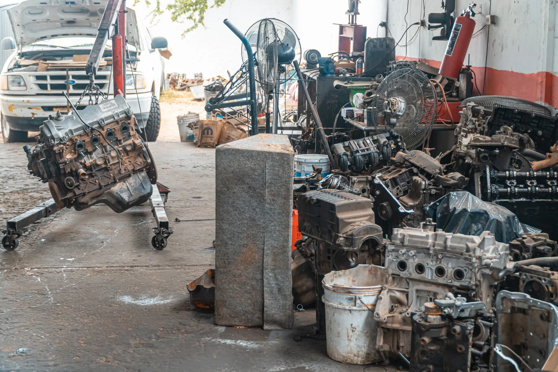 Used car engines and engine parts stacked on the floor of a repair workshop