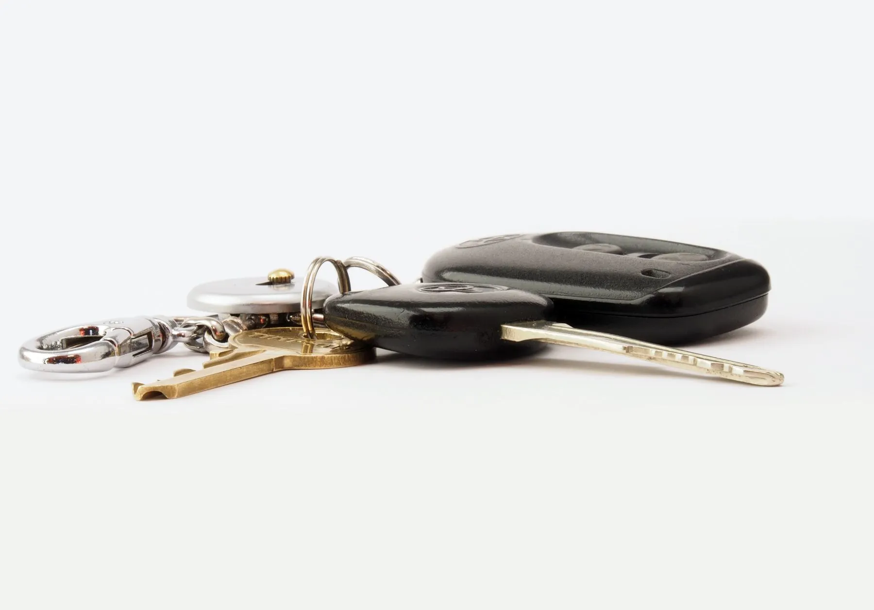 A car key, a remote fob and a ring of house keys lying on a white surface