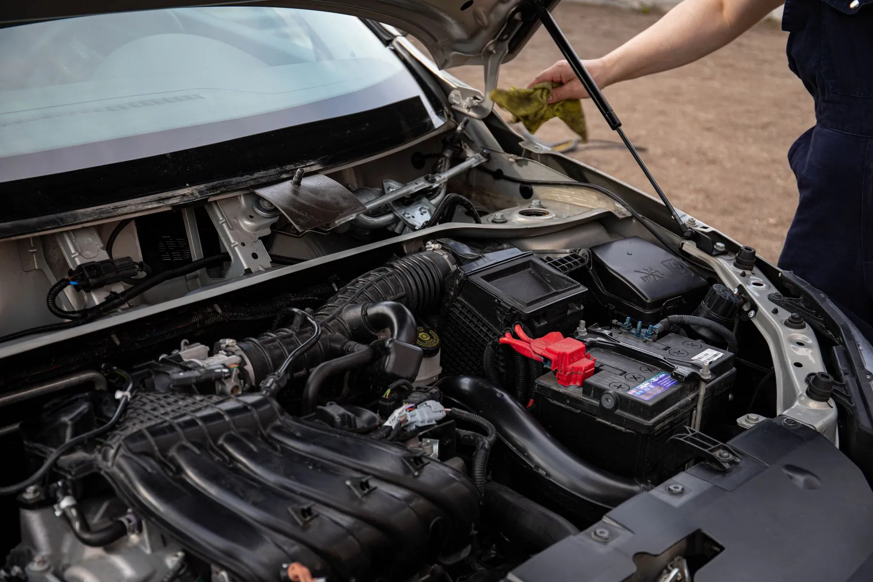 Open hood of a parked car with the engine bay and battery visible